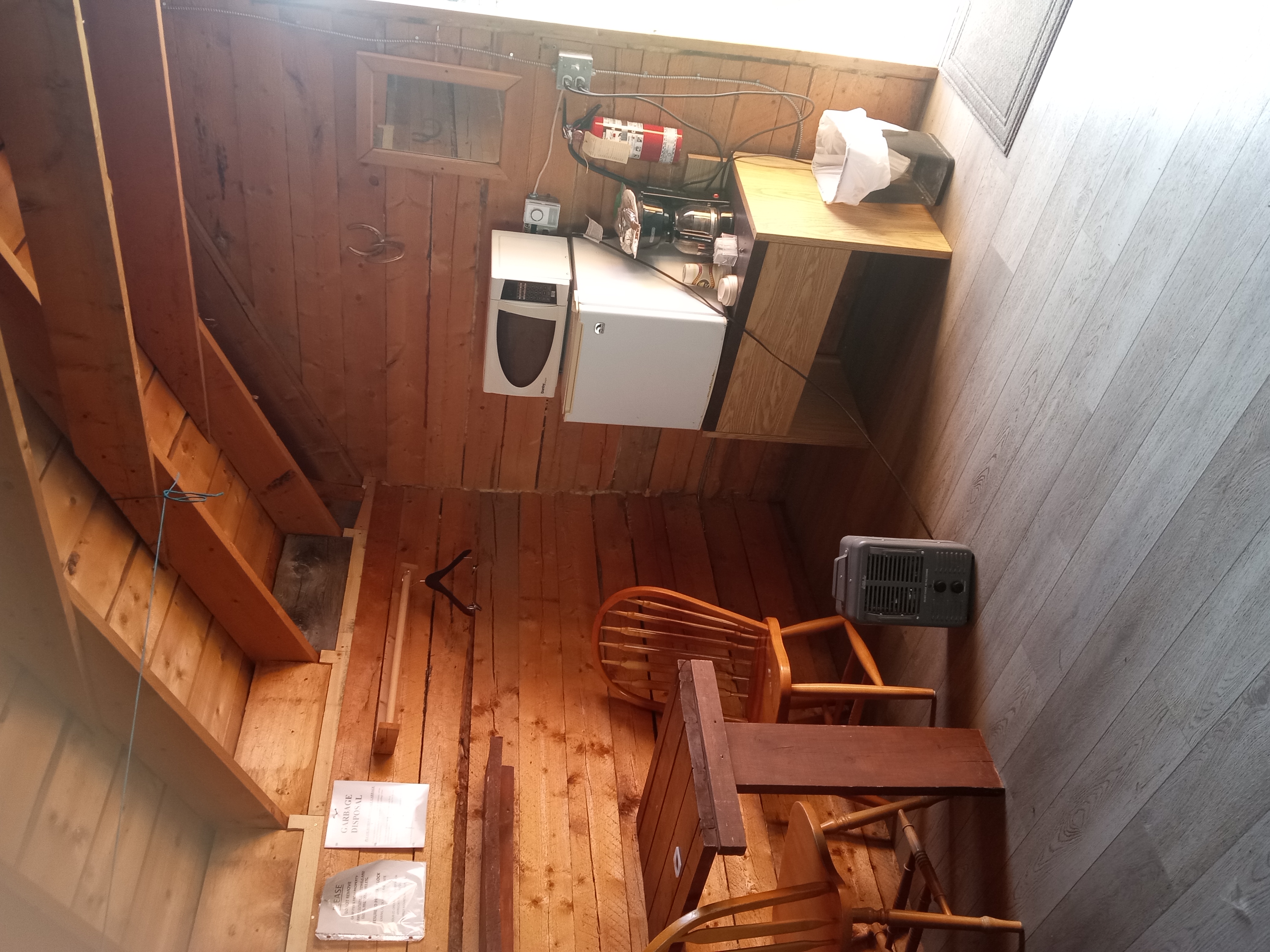 Cabin interior with wood walls, fridge and seating at Barrier Mountain Outfitters